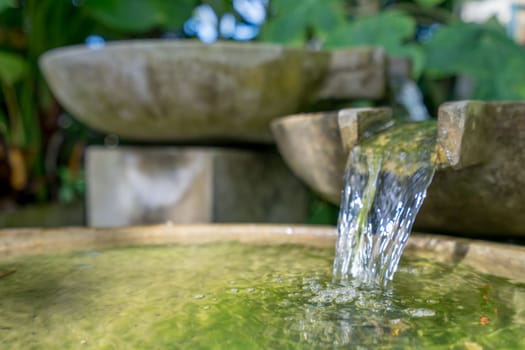 Tropical garden. Image of stone bowl with water flowing. Thailand