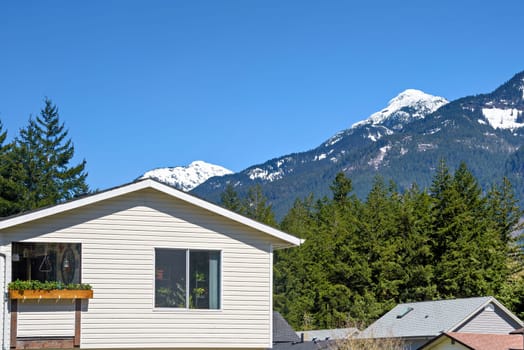 Top of average residential house with mountain view on blue sky background.