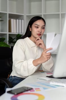 Asian woman freelance graphic designer working with color swatch samples and computer at desk in home office, young lady choosing color gamma for new design project.