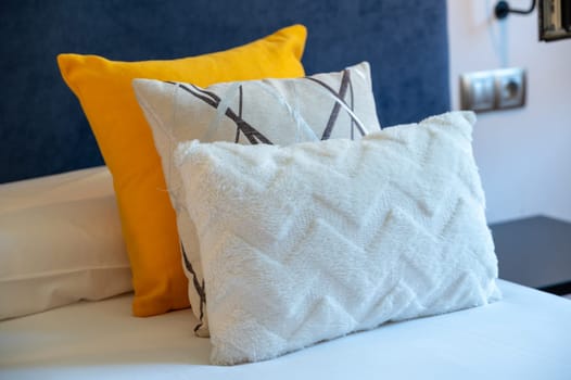 Colorful cushions on bed in illuminated room.