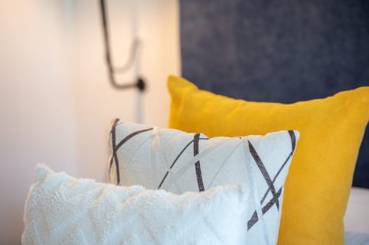 Colorful cushions on bed in illuminated room.