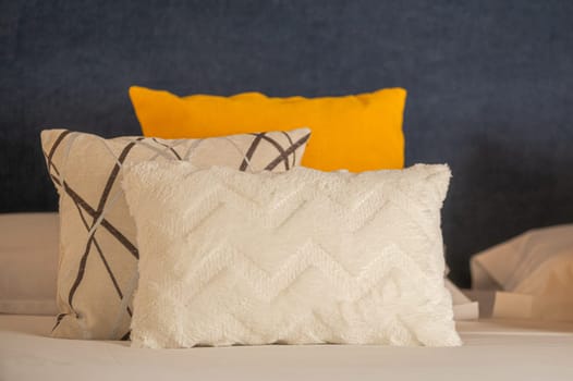 Colorful cushions on bed in illuminated room.