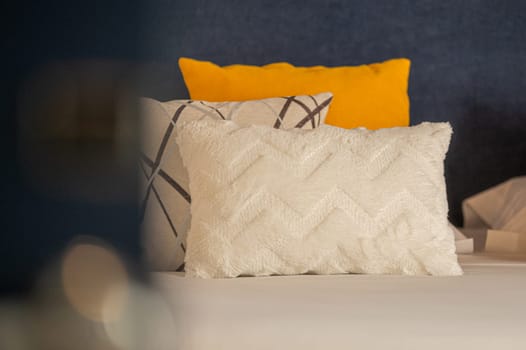 Colorful cushions on bed in illuminated room.