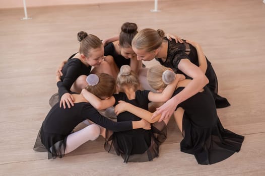 Five little ballerinas and a teacher are sitting in a circle hugging