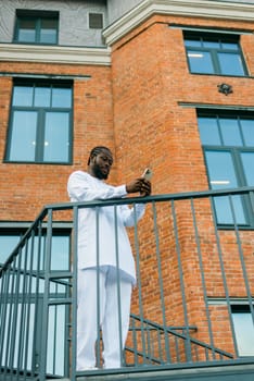 Millennial generation african american man typing sms outdoor 5g internet concept. High speed internet on phone and chatting on social networks and blog