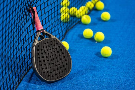 several balls by the net on a blue paddle tennis court. High quality photo