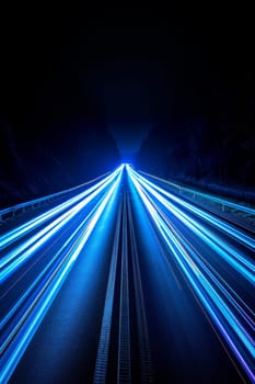 A long blue streak of light is shown on a dark road. The streaks are moving and appear to be coming from a car. Concept of motion and speed, as well as the idea of a busy highway