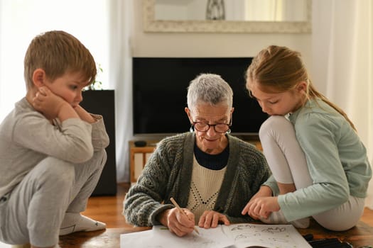 Gray-haired grandmother plays with her little grandchildren in a flat
