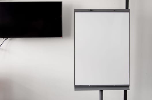 White board or flipchart on white wall background. Background, place for text, copy space.