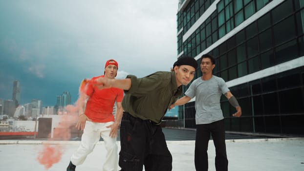 Group of multicultural hipster playing color flare at rooftop. Attractive street dancer holding colored smoke and perform break dance move to hip-hop music. Outdoor sport 2024. Endeavor.