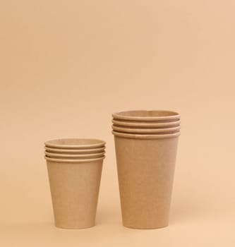 Stack of brown paper disposable cardboard cups on beige background