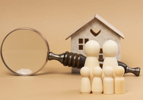 Magnifying glass and a family of wooden figures on the background of a house, the concept of searching for real estate rental, mortgage