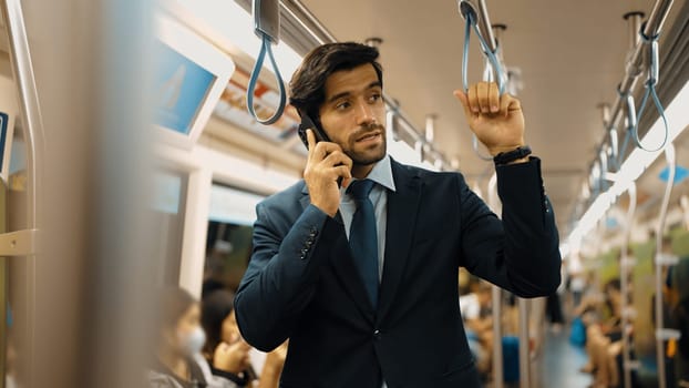 Smart business man phone calling to project manager while standing in train. Professional male leader talking to investor about marketing plan by using phone with blurring background. Exultant.