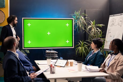Corporate team using greenscreen interactive board display in a workshop meeting, working to improve their skills and productivity. Business workers prepare for successful collaboration.
