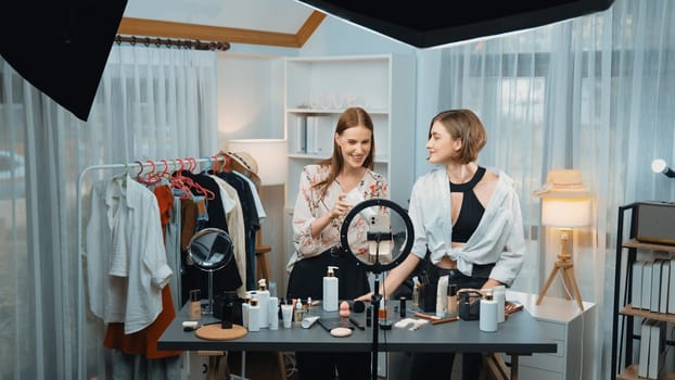 Two women influencer partner shoot live streaming vlog video review skincare for prim social media or blog. Young girl with cosmetic studio lighting for marketing recording session broadcasting online