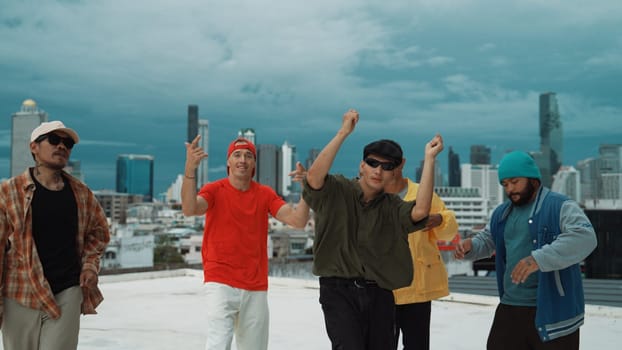 Skilled multicultural street dancing group pose at camera at roof top while moving to the rhyme and music. Young people or teenager moving to funky music, break dance. Outdoor sport 2024. Endeavor.