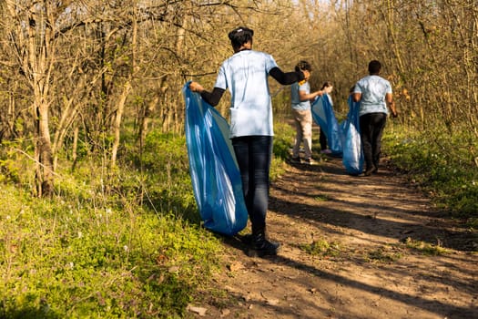 African american climate change volunteer grabbing trash in a bag, working to protect the natural environment. Volunteering for nature conservation and community service action.