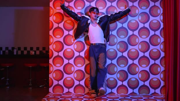 Asian break dancer moving to freestyle music and looking at camera at stage with balloon background. Professional hipster wearing casual outfit and fancy glasses while perform footstep. Regalement.