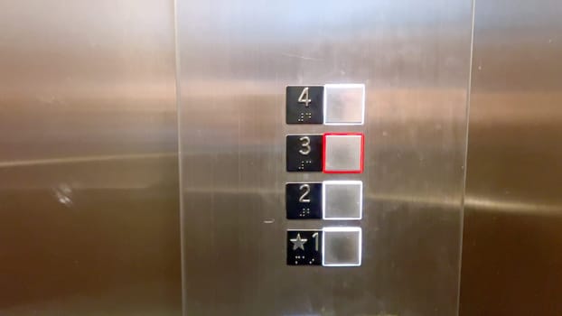 An elevator control panel displaying a set of floor buttons, with the second and third floors highlighted, indicating the current selections made by the users.