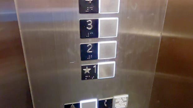 An elevator control panel displaying a set of floor buttons, with the second and third floors highlighted, indicating the current selections made by the users.