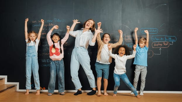 Multicultural happy student and teacher smiling and standing at blackboard with engineering code or prompt written. Kid express feeling of happy and enjoy with studying in STEM classroom. Erudition.