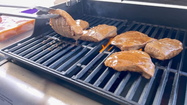 Several thick steaks with grill marks cooking to perfection on an outdoor grill, capturing the essence of a sunny barbecue day.