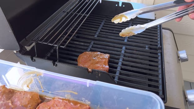 Several thick steaks with grill marks cooking to perfection on an outdoor grill, capturing the essence of a sunny barbecue day.