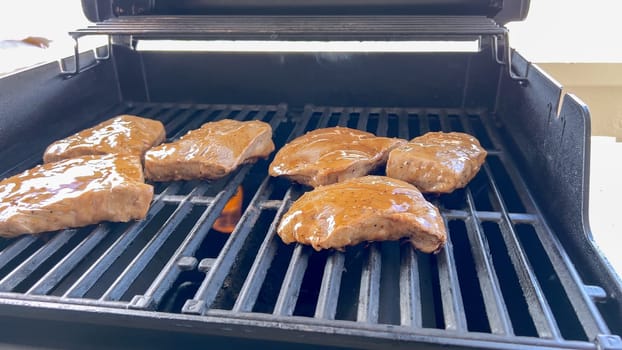 Several thick steaks with grill marks cooking to perfection on an outdoor grill, capturing the essence of a sunny barbecue day.