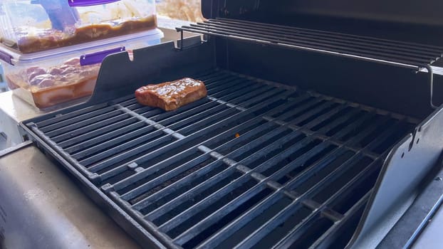 Several thick steaks with grill marks cooking to perfection on an outdoor grill, capturing the essence of a sunny barbecue day.