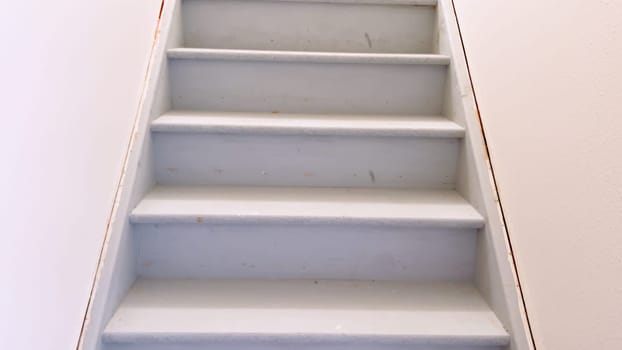 View of a plain white painted staircase descending into the basement of a house, characterized by its clean lines and minimalistic design.