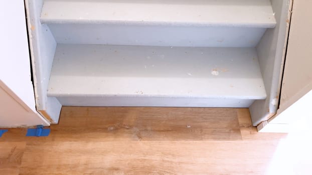 View of a plain white painted staircase descending into the basement of a house, characterized by its clean lines and minimalistic design.