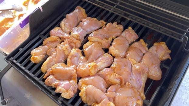 A close-up image capturing the process of grilling marinated chicken pieces, with a person expertly flipping them to ensure even cooking on a classic outdoor barbecue grill.