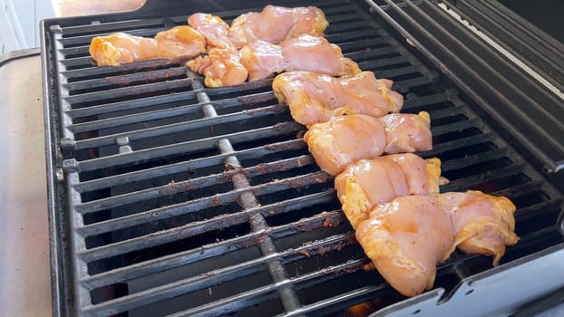 A close-up image capturing the process of grilling marinated chicken pieces, with a person expertly flipping them to ensure even cooking on a classic outdoor barbecue grill.