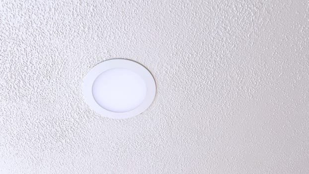 A simple and modern ceiling light fixture is centrally positioned against a textured white ceiling, providing clean and efficient illumination within a room.