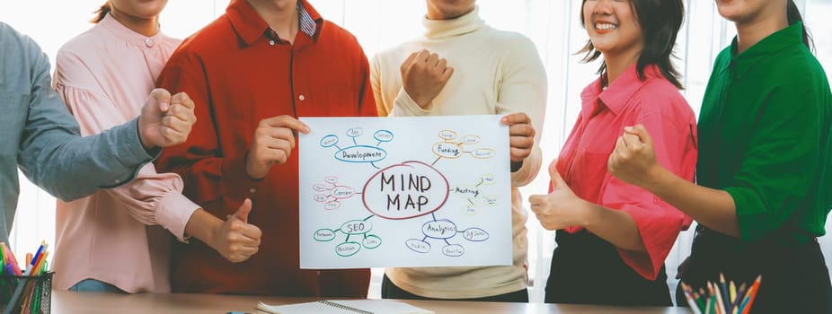 A cropped image of successful businesspeople presents new product marketing strategy using a mind map. Young creative business team brainstorm marketing idea together at modern office. Variegated.