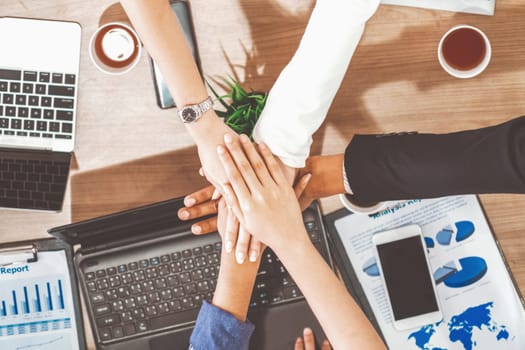 Businessmen and businesswomen joining hands in group meeting at multicultural office room showing teamwork, support and unity in business. Diversity workplace and corporate people working concept. uds