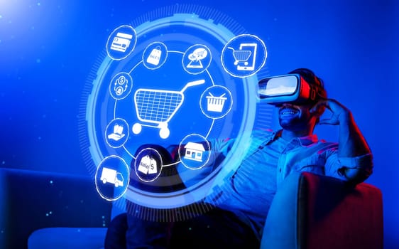 Happy man using VR headset and shopping online while sitting at sofa with shopping bags. Smart person looking at online market hologram and icon with neon background. Innovation technology. Deviation.