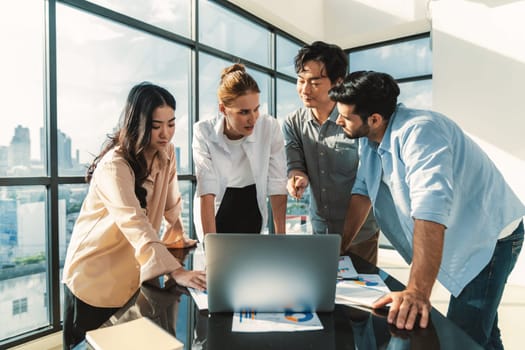 Asian project manager uses laptop displayed data analysis while professional business team brainstorming marketing idea at business meeting. Working together,sharing idea, planing strategy. Tracery.