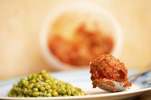 meatball in sauce with a side of peas