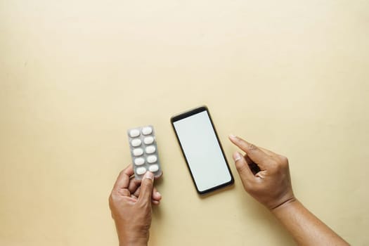 young man hand holding a medicine and smart phone on color background .