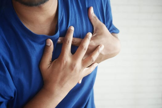 young man suffering pain in heart and holding chest with hand .