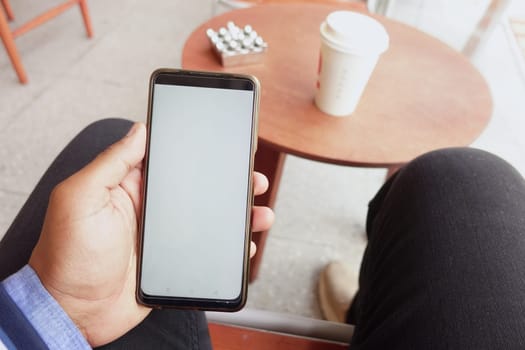 pov shot or young man hand using smart phone sitting on cafe .