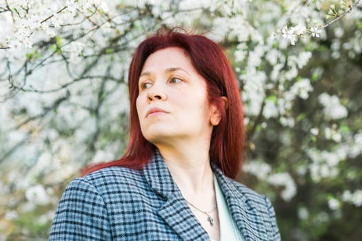 Beautiful happy millennial woman enjoying smell in a flowering spring garden. Blooming tree time.