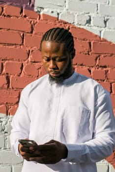 Millennial generation african american man typing sms outdoor 5g internet concept. High speed internet on phone and chatting on social networks and blog