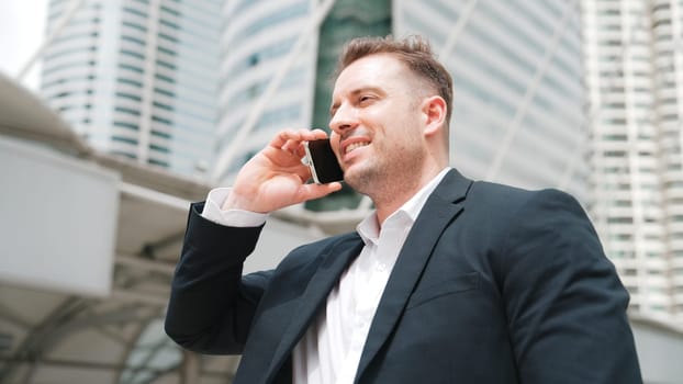 Smart caucasian businessman calling his colleague to plan financial strategy while standing at urban city. Project manager using his mobile phone to communicate with marketing team. Lifestyle. Urbane.