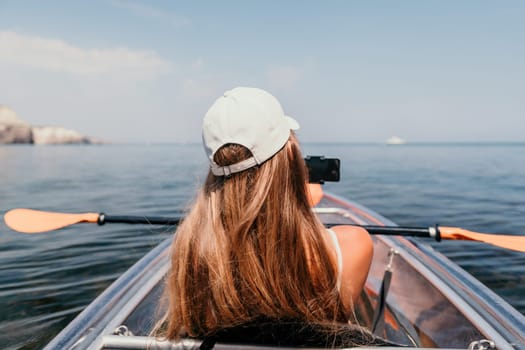 Woman in kayak back view. Happy young woman with long hair floating in transparent kayak on the crystal clear sea. Summer holiday vacation and cheerful female people having fun on the boat.