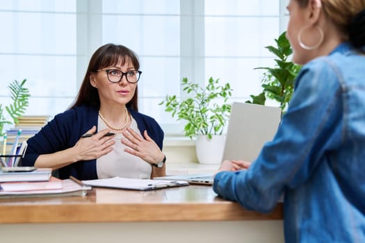 Female psychologist therapist working with young teen girl sitting in office. Teenage female student at therapy meeting with counselor. Psychology therapy psychotherapy youth mental health treatment