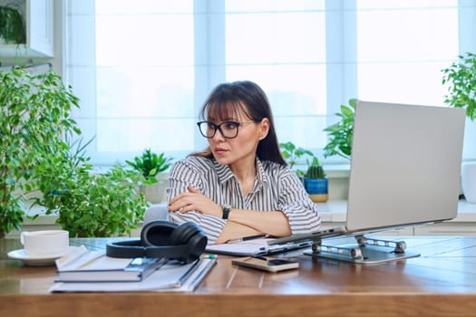 Sad upset tired businesswoman sitting at workplace with computer laptop in home office. Difficulties, problems in business, work