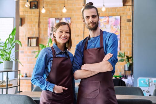 Small business team portrait of confident successful colleagues partners young man woman in aprons posing looking at camera at workplace in restaurant coffee shop cafeteria. Partnership teamwork work