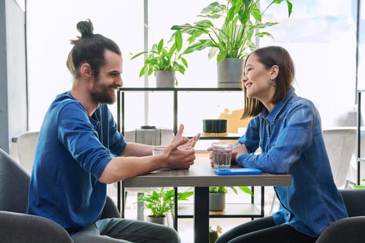 Laughing rejoicing cheerful young couple sitting together at table in cafe. Joyful emotions, enjoyment, friendship, happiness, love, togetherness, lifestyle relationships communication youth concept